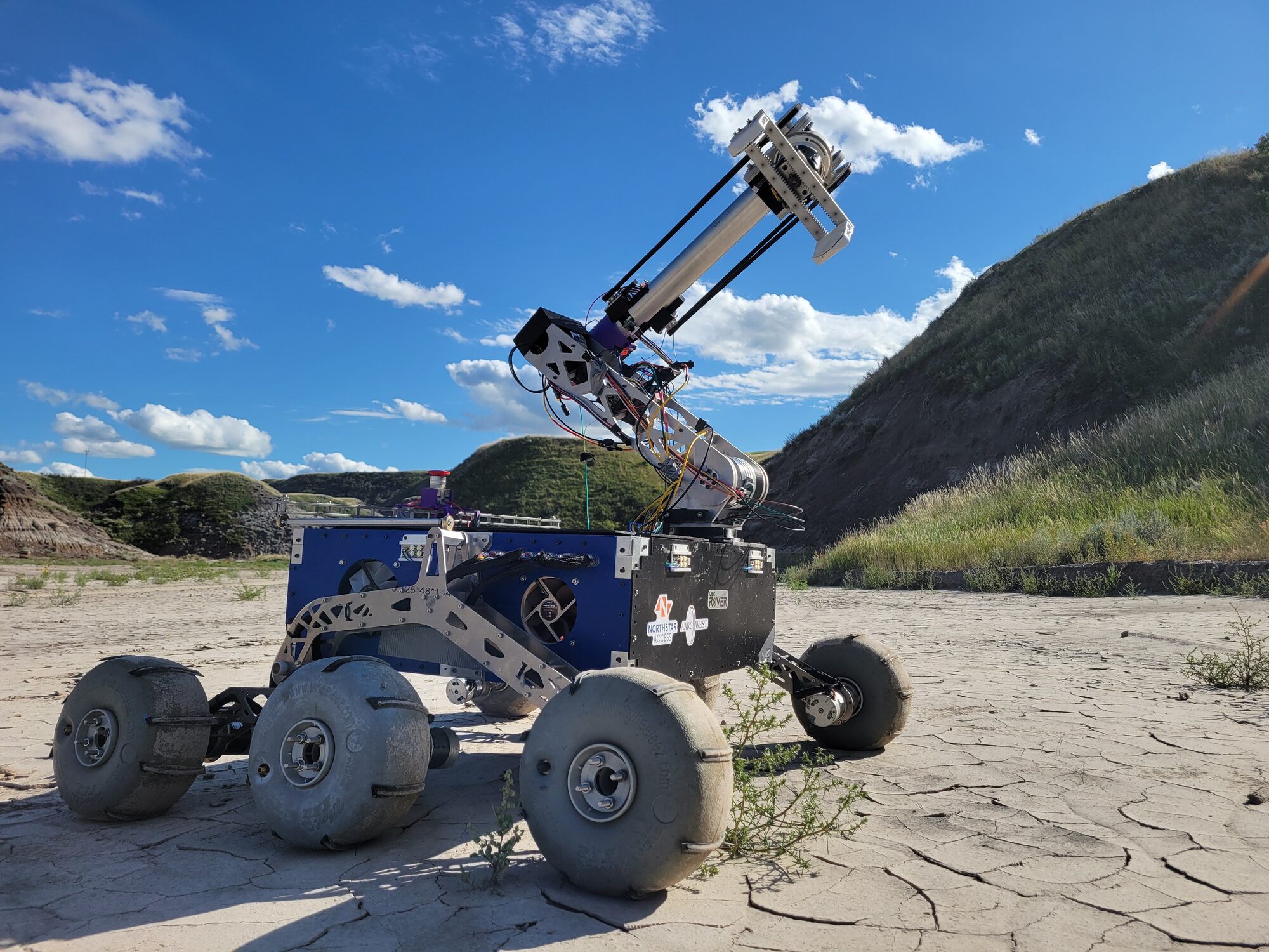 The UBC Rover vehicle deployed on desert terrain with its robotic arm extended.